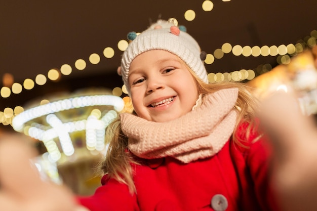 Kleines Mädchen macht ein Selfie auf dem Weihnachtsmarkt