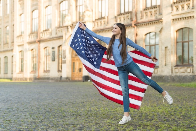 Kleines Mädchen mit amerikanischer Flagge im Freien Architektur Hintergrund Museum nationales Geschichtskonzept