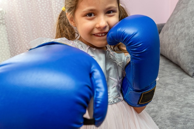 Kleines Mädchen mit blauen Boxhandschuhen und einem Festtagskleid mit Sternen