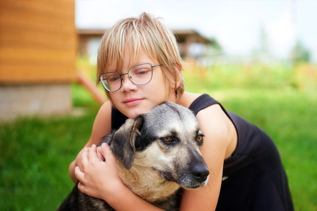 Kleines Mädchen mit Brille, die einen großen Hund umarmt