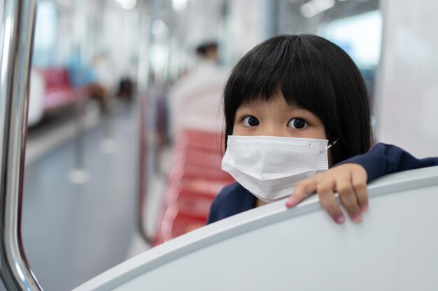 Kleines Mädchen mit chirurgischer Maske Gesichtsschutz Grippe und Virusausbruch in öffentlichen Verkehrsmitteln