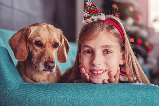 Kleines Mädchen mit dem gelben Hund, der auf Sofa aufwirft