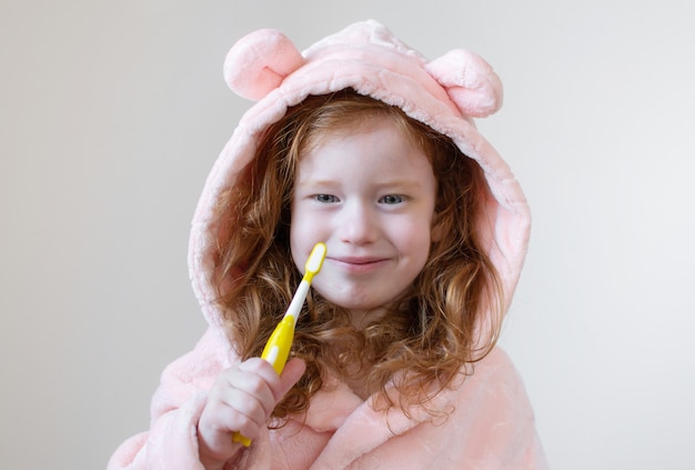 Kleines Mädchen mit dem Ingwer-Haar, das ihre Zähne, gelbe Zahnbürste, Zahnpflege, Morgen-Nachtgesunder Konzept-Lebensstil putzt