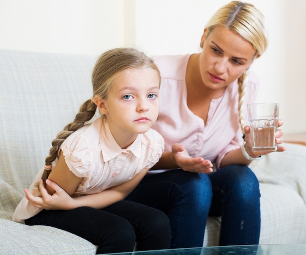 Kleines Mädchen mit den Schmerz im Bauch und in der besorgten Mutter zuhause