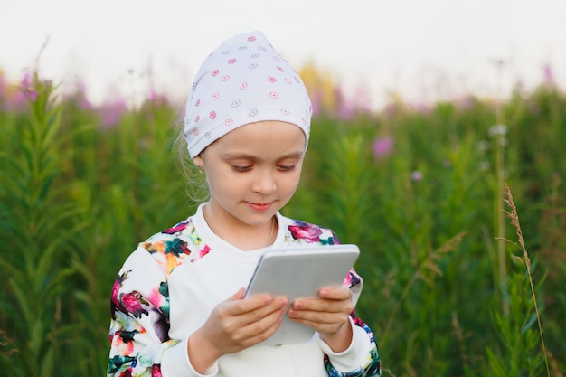 Kleines Mädchen mit digitaler Tablette auf der Natur