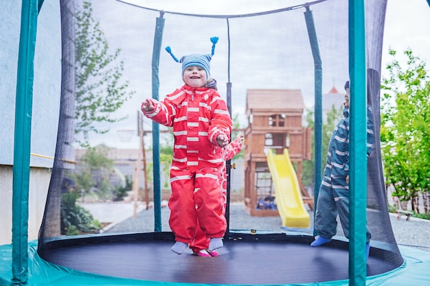 Kleines Mädchen mit Down-Syndrom springt auf ein Trampolin. Sie ist glücklich. selektiver Fokus