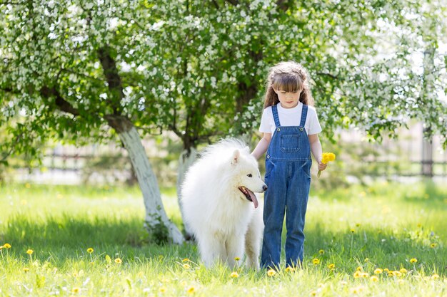 Kleines Mädchen mit einem großen weißen Hund im Park.