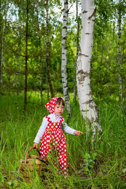 Kleines Mädchen mit einem Korb voller Pilze im Wald.