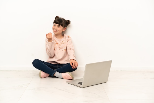 Kleines Mädchen mit einem Laptop, der auf dem Boden sitzt und einlädt, mit der Hand zu kommen. Schön, dass du gekommen bist