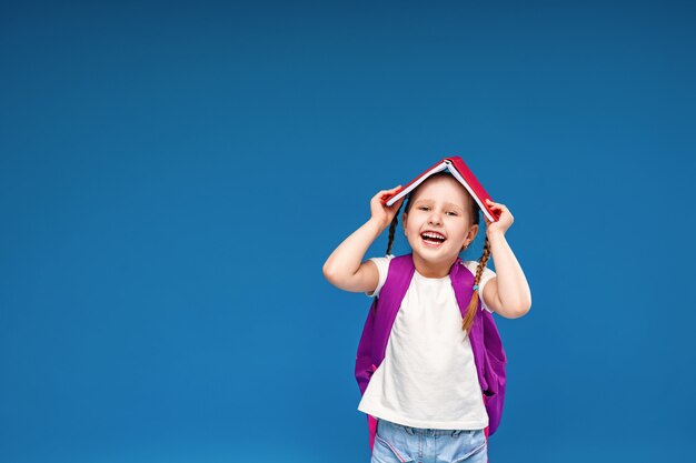 Kleines Mädchen mit einem Rucksack und einem Buch