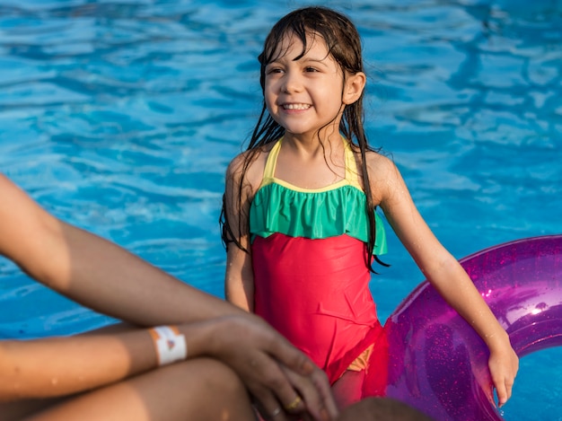 Kleines Mädchen mit einem Sommerfloss im Pool