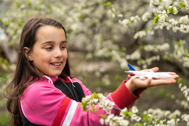 Kleines Mädchen mit einem Spielzeugflugzeug im Garten