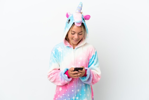 Kleines Mädchen mit Einhorn-Pyjama isoliert auf weißem Hintergrund, das eine Nachricht mit dem Handy sendet