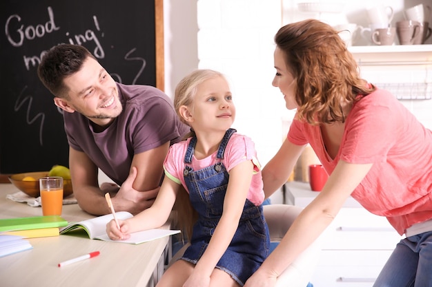 Kleines Mädchen mit Eltern, die zu Hause Hausaufgaben machen