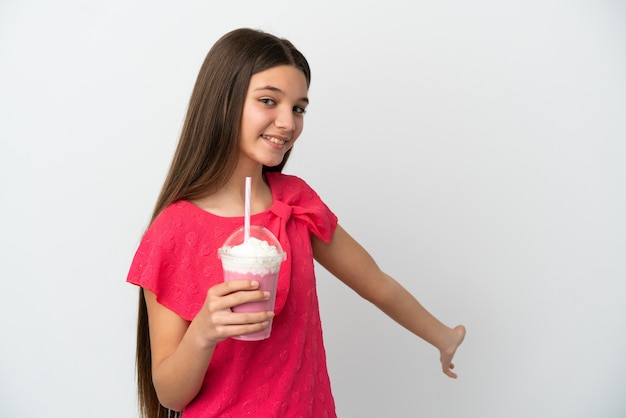 Kleines Mädchen mit Erdbeermilchshake über isoliertem weißem Hintergrund, das die Hände zur Seite ausstreckt, um zum Kommen einzuladen