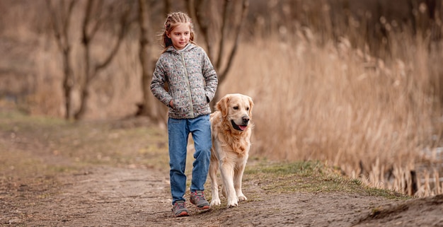 Kleines Mädchen mit Frisur und Golden Retriever Hund stehend und zurückblickend