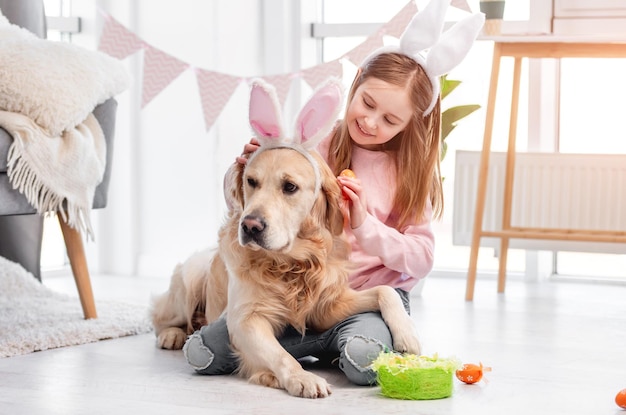 Kleines Mädchen mit Golden Retriever-Hund zu Ostern