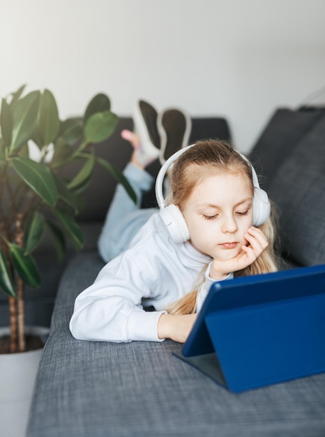 Kleines Mädchen mit Kopfhörern und Tablet zu Hause