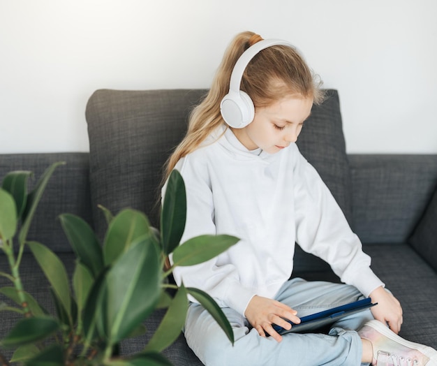 Kleines Mädchen mit Kopfhörern und Tablet zu Hause