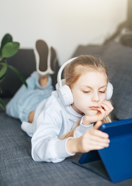 Kleines Mädchen mit Kopfhörern und Tablet zu Hause