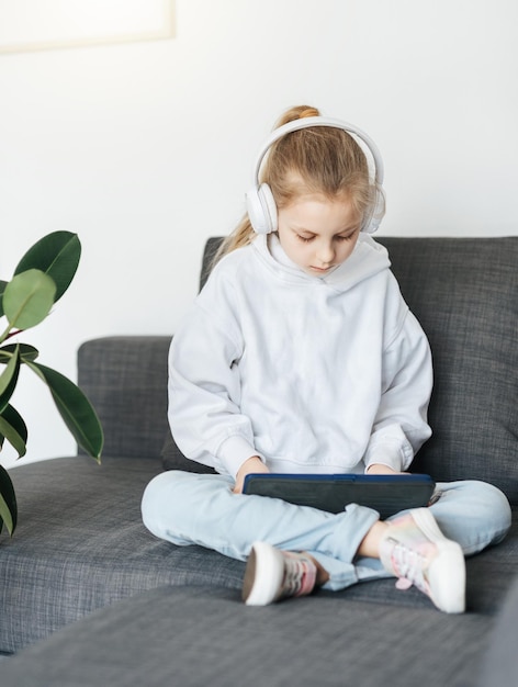 Kleines Mädchen mit Kopfhörern und Tablet zu Hause