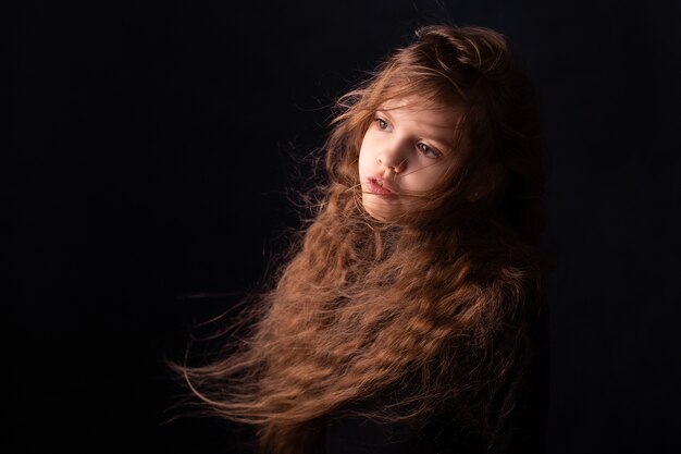 kleines Mädchen mit langen Haaren auf einem schwarzen