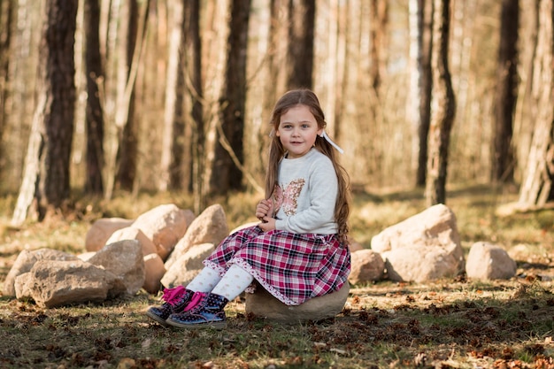 kleines Mädchen mit langen Haaren im Wald sitzen