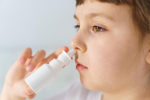 Kleines Mädchen mit laufender Nase macht Nasenspray-Bewässerungen, um allergische Rhinitis und Sinusitis zu stoppen