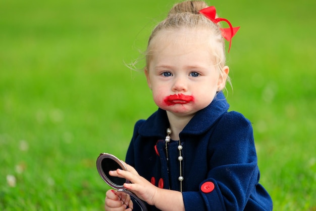 Kleines Mädchen mit Lippenstiftflecken im Gesicht