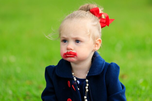 Kleines Mädchen mit Lippenstiftflecken im Gesicht