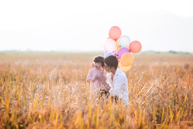 Kleines Mädchen mit Luftballons auf Weizenfeld spielen