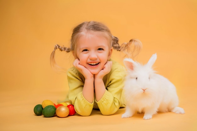 kleines Mädchen mit Osterhasen auf gelbem Grund