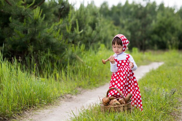 Kleines Mädchen mit Pilzen im Wald