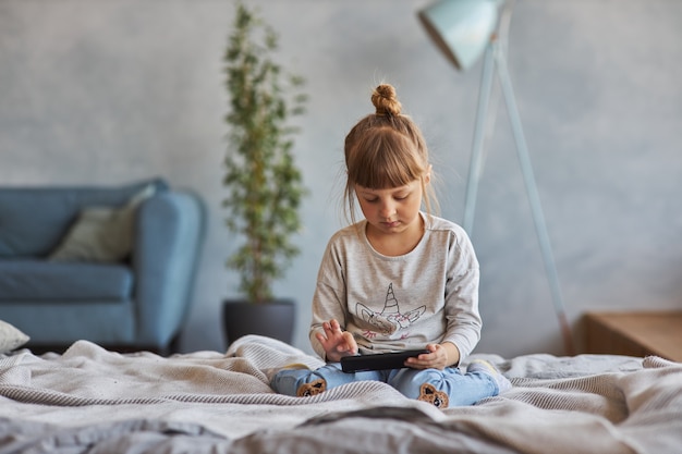 kleines Mädchen mit Smartphone zu Hause