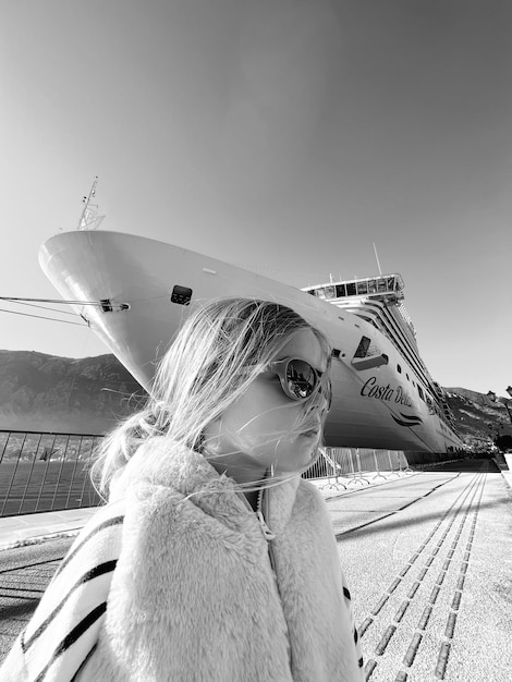 Kleines Mädchen mit Sonnenbrille vor dem Hintergrund eines Schwarz-Weiß-Fotos eines Kreuzfahrtschiffes