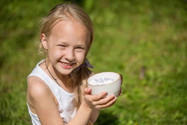 Kleines Mädchen mit Tasse Milch in der Natur