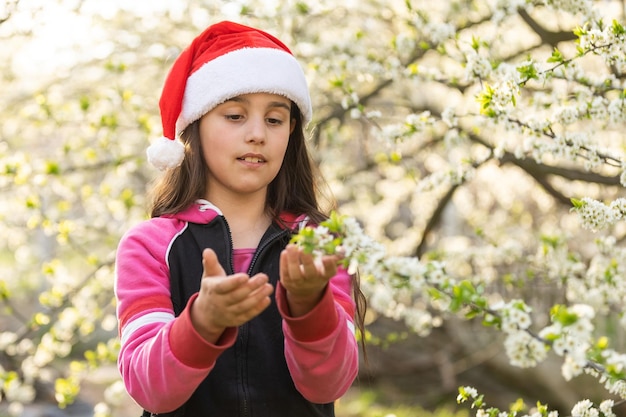Kleines Mädchen mit Weihnachtsmütze, das im Garten spielt