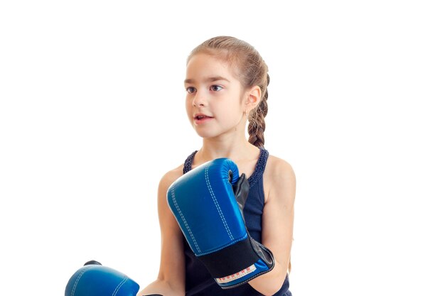 Kleines Mädchen mit Zöpfen in Boxhandschuhen schaut isoliert auf weißem Hintergrund
