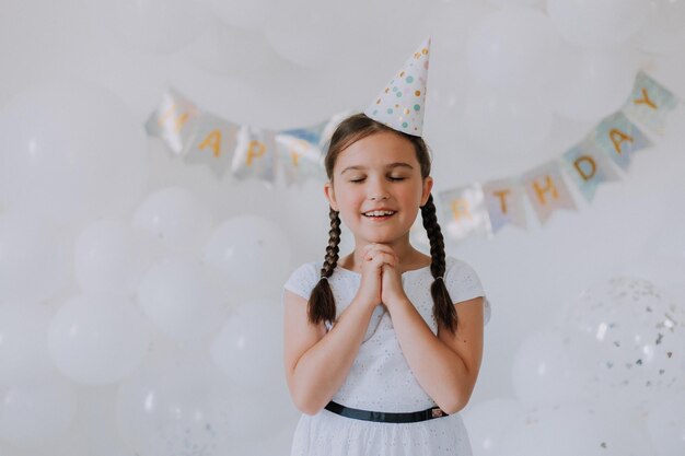 Kleines Mädchen mit zwei Zöpfen in einem weißen Kleid feiert ihren Geburtstag