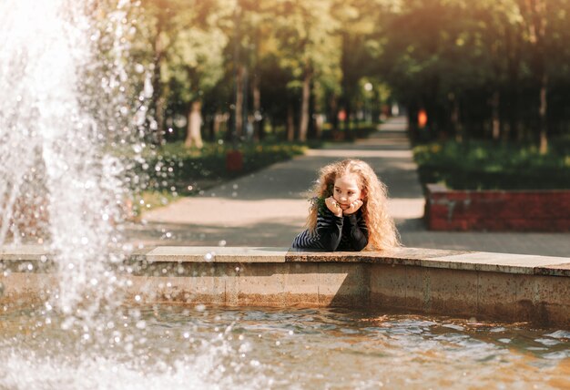 Foto kleines mädchen nahe dem brunnen im park im sommer park