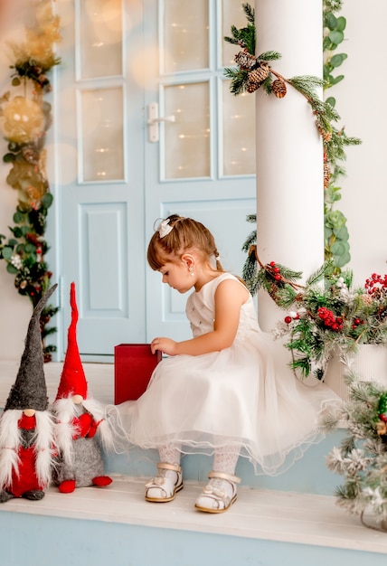 Kleines Mädchen öffnet ein Weihnachtsgeschenk.