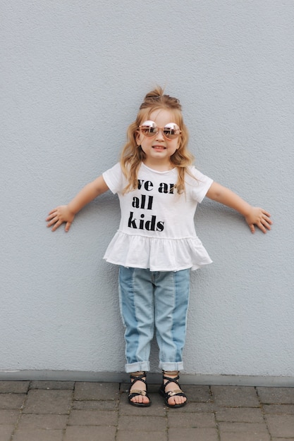 Kleines Mädchen probiert Sonnenbrille an und posiert zum Fotografen.