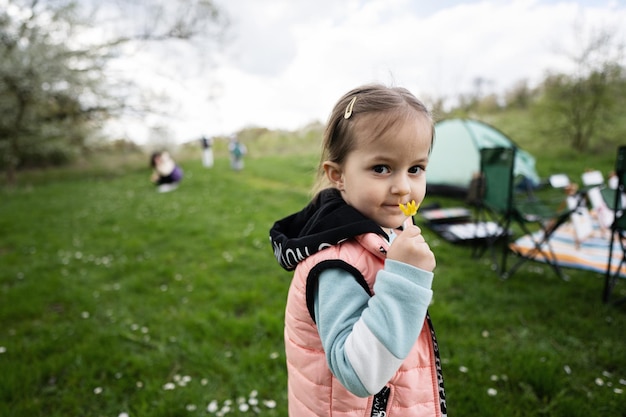Kleines Mädchen schnüffelt an einer gelben Blume auf der Frühlingswiese
