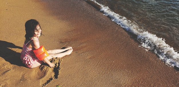 Kleines Mädchen sitzen am Strand