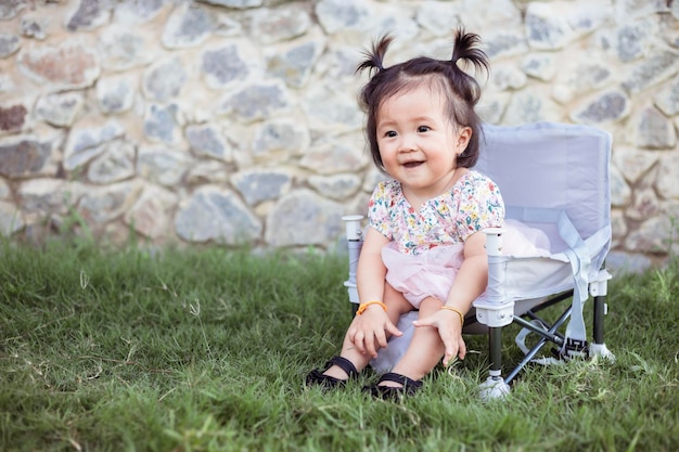 Kleines Mädchen sitzt auf einem Picknickstuhl im Park im Outdoor-Urlaub im Sommer Schönes Mädchen süße Tochter reist beim Camping im Garten Bild eines süßen kleinen Mädchens