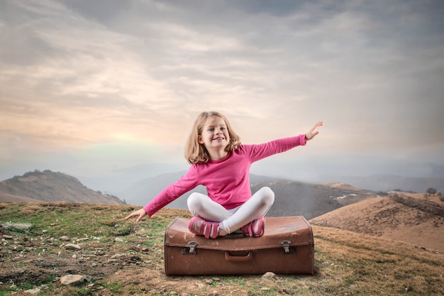 Kleines Mädchen sitzt auf einem Reisekoffer