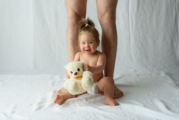 Kleines Mädchen sitzt glücklich und Beine ihres Vaters