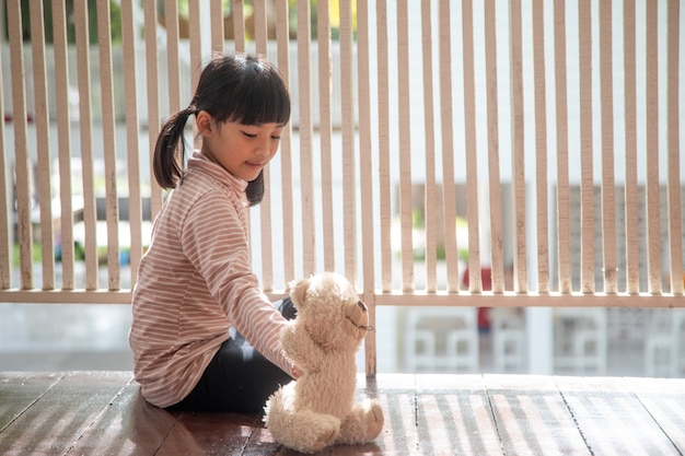 Kleines Mädchen sitzt im Wohnzimmer mit Teddybär