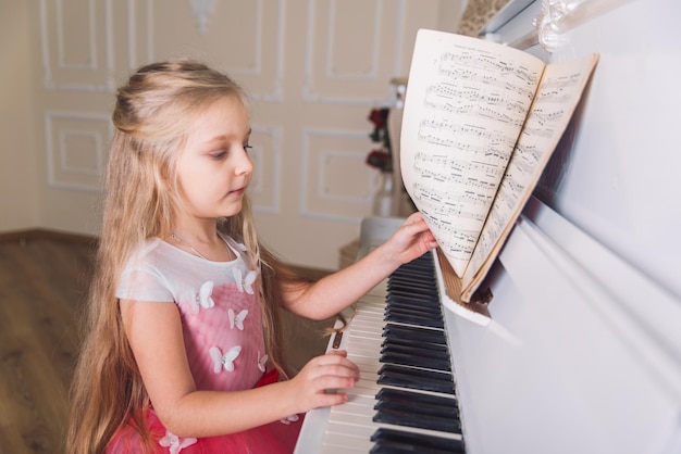 Kleines Mädchen spielt am Klavier im Kleid