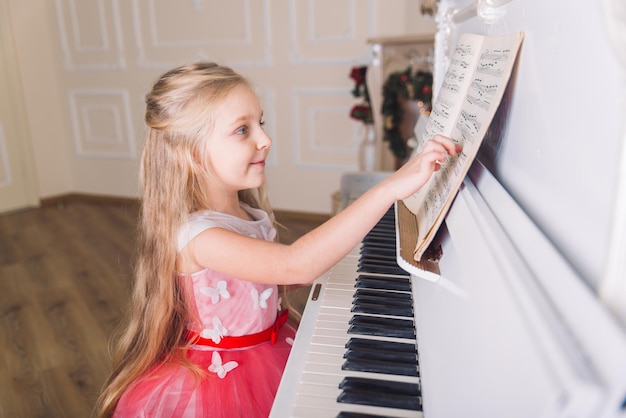 Kleines Mädchen spielt am Klavier im Kleid